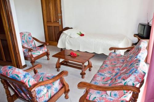 uma sala de estar com cadeiras, uma cama e uma mesa em Villa de Roses em Beau Vallon
