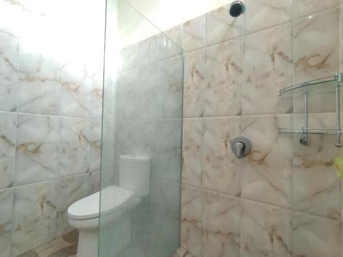 a bathroom with a toilet and a glass shower at Adi Pelita Sari Bali in Denpasar