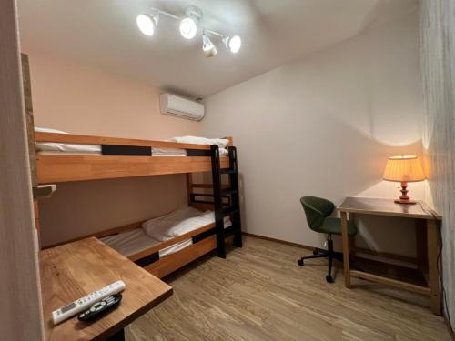 Naoshima Backpackers Guesthouse في ناووشيما: غرفة مع سرير بطابقين ومكتب مع مصباح