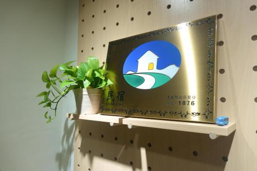 a sign on a wall with a plant on a shelf at Kozy Stay in Taitung City