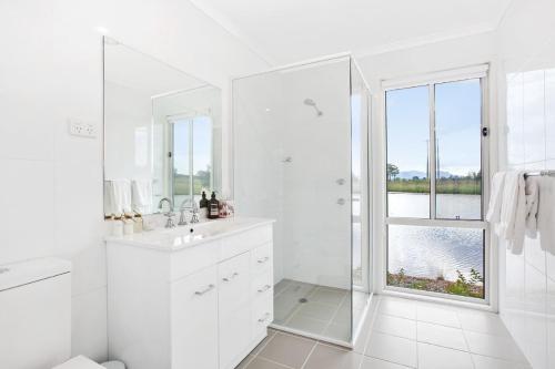 a white bathroom with a sink and a window at Romantic lakehouse set in a private vineyard in the Hunter Valley in Lovedale