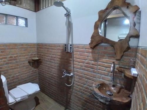 a brick bathroom with a sink and a mirror at Dem Ayem Heritage Guest House in Yogyakarta