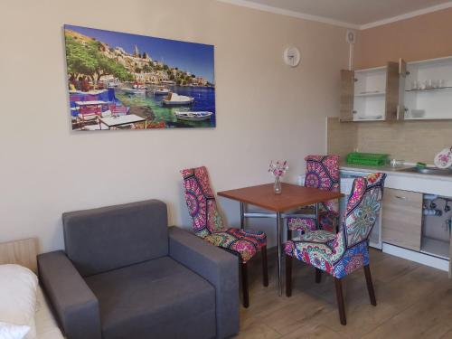ein Wohnzimmer mit einem Stuhl und einem Tisch sowie eine Küche in der Unterkunft Liwia 2 in Niechorze