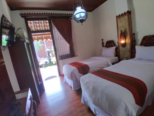 a hotel room with two beds and a window at Dem Ayem Heritage Guest House in Yogyakarta