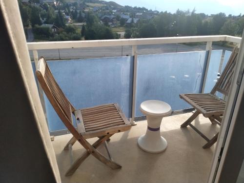 a balcony with two chairs and a stool on a ship at STUDIO la TOUSSUIRE EN SAVOIE in La Toussuire