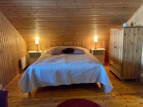 1 dormitorio con 1 cama en una habitación de madera en Villa Huvikalliola, LaatuLomat, en Sulkava