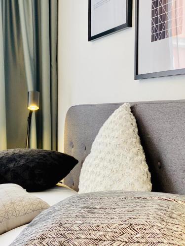 a bed with black and white pillows and a lamp at Pension MONO - Adults Only in Český Krumlov