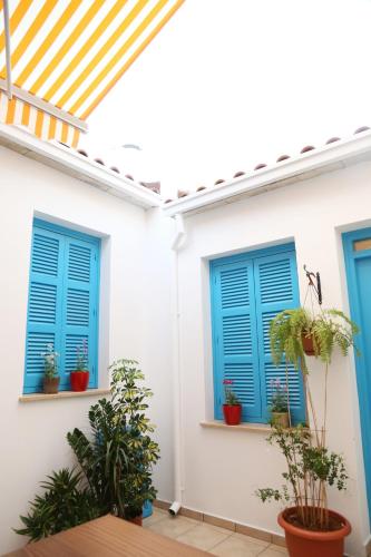 a white house with blue shutters and potted plants at Cypriot Swallow Boutique Hotel in North Nicosia