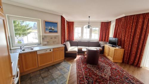 a kitchen with a living room with a couch and a tv at Sport und Familienhotel Klausen in Kirchberg in Tirol