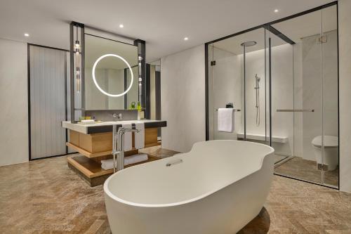 uma casa de banho com uma banheira, um lavatório e um espelho. em Artyzen Lingang Shanghai em Xangai