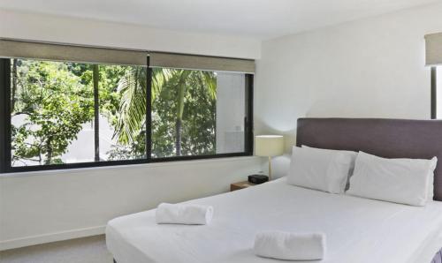 a bedroom with a white bed and a large window at Little Cove Court - Apt 10 in Noosa Heads