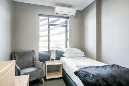 a bedroom with a bed and a chair and a window at Illinois Hotel in Sydney