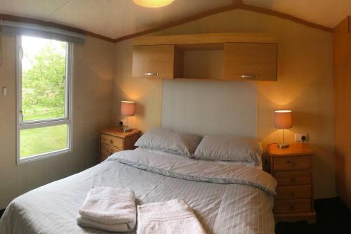 a bedroom with a bed with two towels on it at Plum Tree Lodge Set in 2 acres of Private Land in Coundon