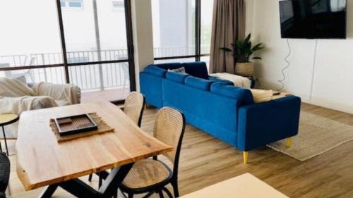 a living room with a blue couch and a table at #7 Highlander, Kings Beach - Beachfront Complex in Caloundra