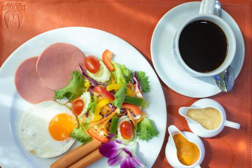 einen Teller mit einem Ei, einem Salat und einer Tasse Kaffee in der Unterkunft The Wing Design Hotel in Bangkok