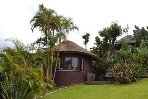 a small house with a thatched roof in a garden at Fish Eagle Manor in East London