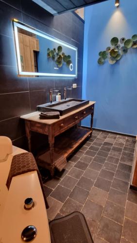 a bathroom with a wooden sink and a mirror at Een vleugje wellness in de Voerstreek - Bed & Brocante Onder de Poort in Voeren