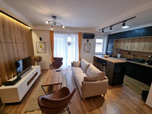 Una sala de estar con un sofá y sillas y una cocina. en Lovely 1-bedroom rental unit with free parking, en Skopje