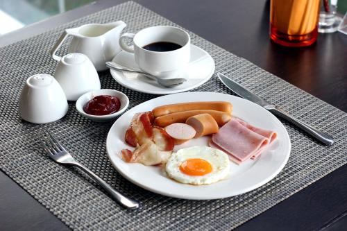 a plate of breakfast food on a table with a cup of coffee at The Seashore Kamala Service Apartment in Kamala Beach