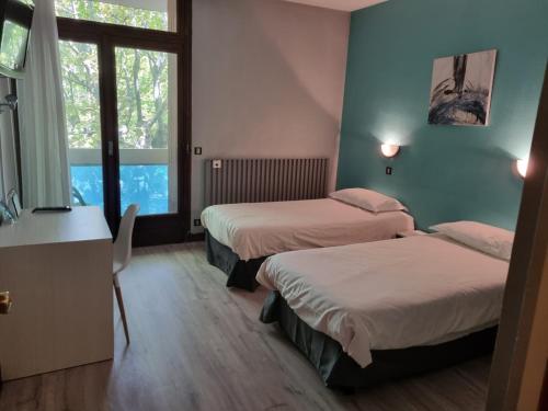 a hotel room with two beds and a window at Hotel Le Comty in Feurs
