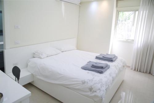 Un dormitorio blanco con una cama con toallas. en Dizengoff - Lovely family apartment 3 rooms., en Tel Aviv