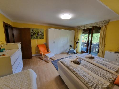 - une chambre avec deux lits et une chaise orange dans l'établissement Haus Flora - Ferienwohnung Bodensdorf, à Bodensdorf