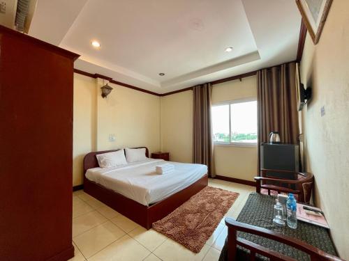 ein Hotelzimmer mit einem Bett und einem TV in der Unterkunft Sengkeo Hotel in Vientiane