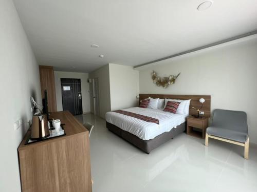 a bedroom with a bed and a desk and a chair at Christella Hotel Laemchabang in Si Racha