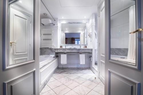 un bagno bianco con vasca e lavandino di Hôtel Le Lavoisier a Parigi