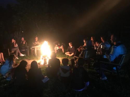 a group of people sitting around a fire at night at Căsuțele Doftanei in Teşila