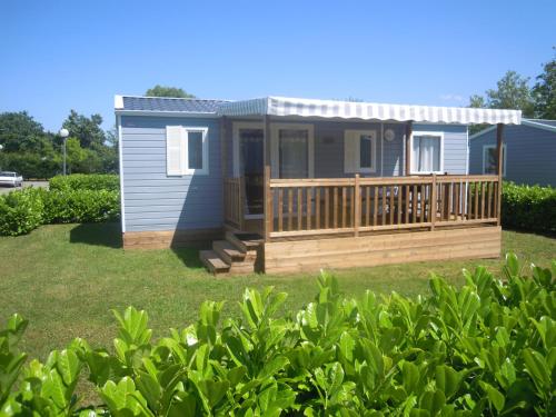a tiny house with a porch and a deck at Camping Le Beaulieu in Puilboreau