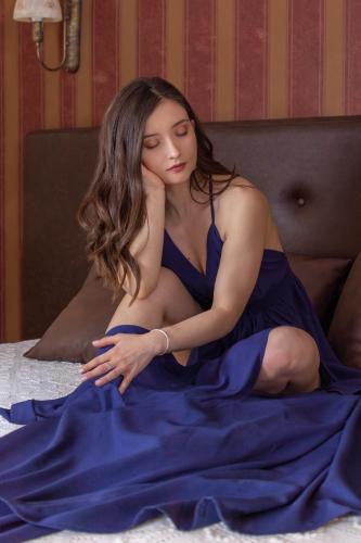 a woman in a blue dress sitting on a bed at Hagiati Anastasiou Hotel & Spa in Naousa Imathias
