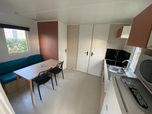 a small kitchen with a table and chairs in a room at Camping Le Beaulieu in Puilboreau