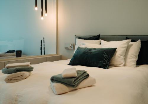 Una cama con toallas y almohadas. en B&B De Tiendeschuur, en Evergem
