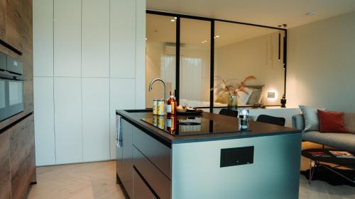 a kitchen with a counter and a living room at B&B De Tiendeschuur in Evergem