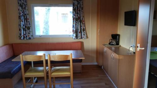 a kitchen with two chairs and a table and a window at Camping Le Beaulieu in Puilboreau