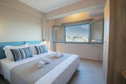 1 dormitorio con 1 cama grande y ventana en Heraclea Luxury Suites, en Nea Iraklia