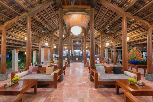 a pavilion with tables and couches and wooden ceilings at Pilgrimage Village Boutique Resort & Spa in Hue