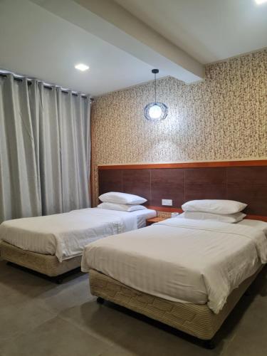 two beds in a hotel room with two beds sidx sidx sidx at Hotel Bestari in Kuala Lipis