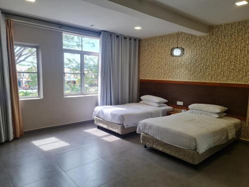 a hotel room with two beds and a window at Hotel Bestari in Kuala Lipis