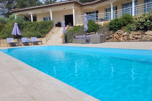 une piscine avec de l'eau bleue devant une maison dans l'établissement VILLA BELLAVISTA, aux Arcs-sur-Argens