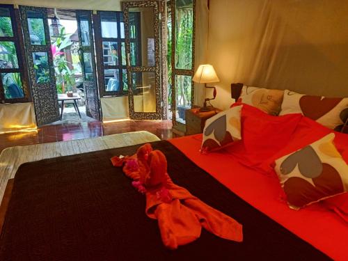 a bedroom with a bed with red sheets and pillows at Funky Place in Lovina