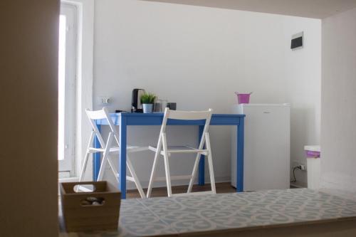escritorio azul con 2 sillas y nevera en Terrasini 2000 Home Holidays, en Terrasini