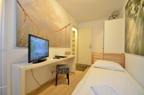 een slaapkamer met een bed en een bureau met een televisie bij Ajo Vienna Siemens - Contactless Check-in in Wenen
