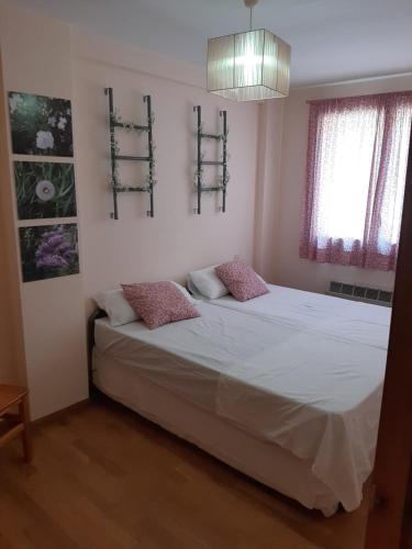 um quarto com uma cama com lençóis brancos e almofadas cor-de-rosa em Apartamento Canfranc em Canfranc