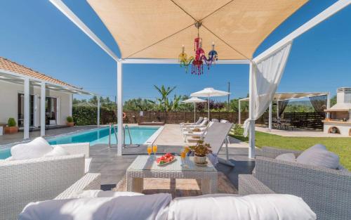 un patio con tavolo, sedie e piscina di Madini Luxury villa with private heated pool a Vanáton