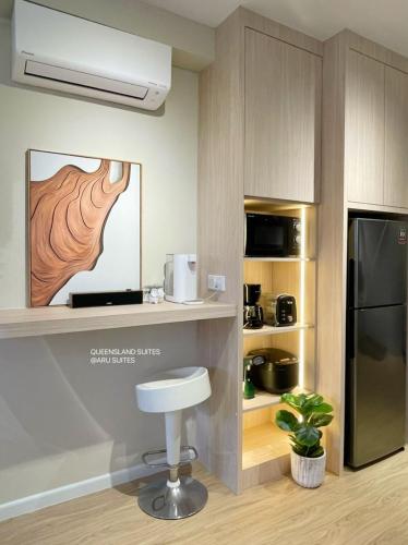 a kitchen with a counter with a refrigerator and a stool at QUEENSLAND SUITES at Aru Suites, Kota Kinabalu in Kota Kinabalu