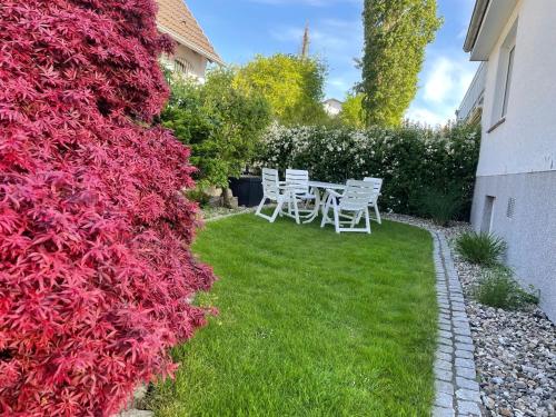 a garden with white chairs and red plants at Ferienwohnung Ostseewellen in Timmendorfer Strand