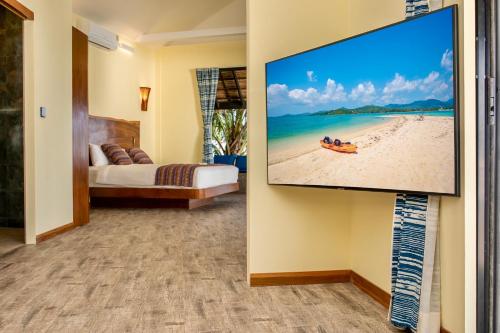 a room with a flat screen tv hanging on a wall at Absolute Beachfront Villas in Ban Tai