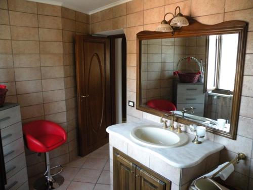 baño con lavabo, espejo y taburete rojo en Villa Carlotta, en Isernia